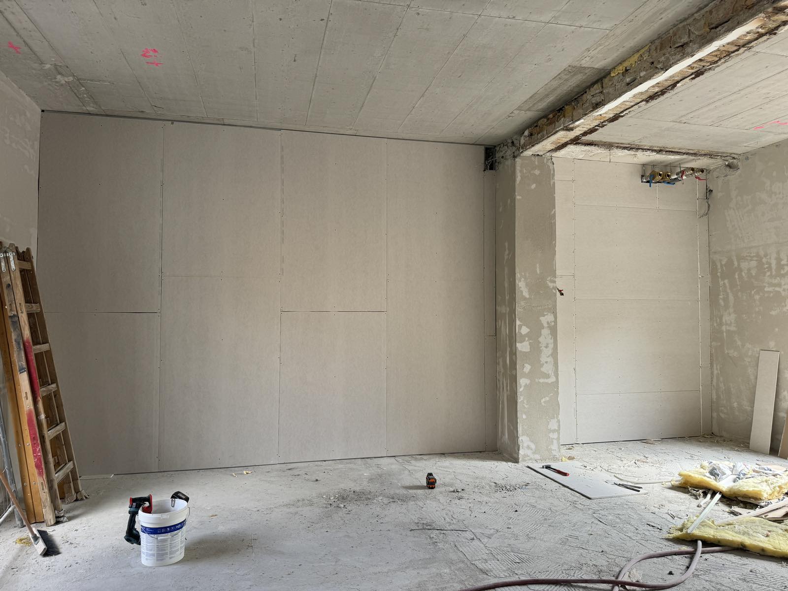Gipszkarton előtétfal borítás: felcsavarozott lapok betonpillér mellett, glettelés előtt.